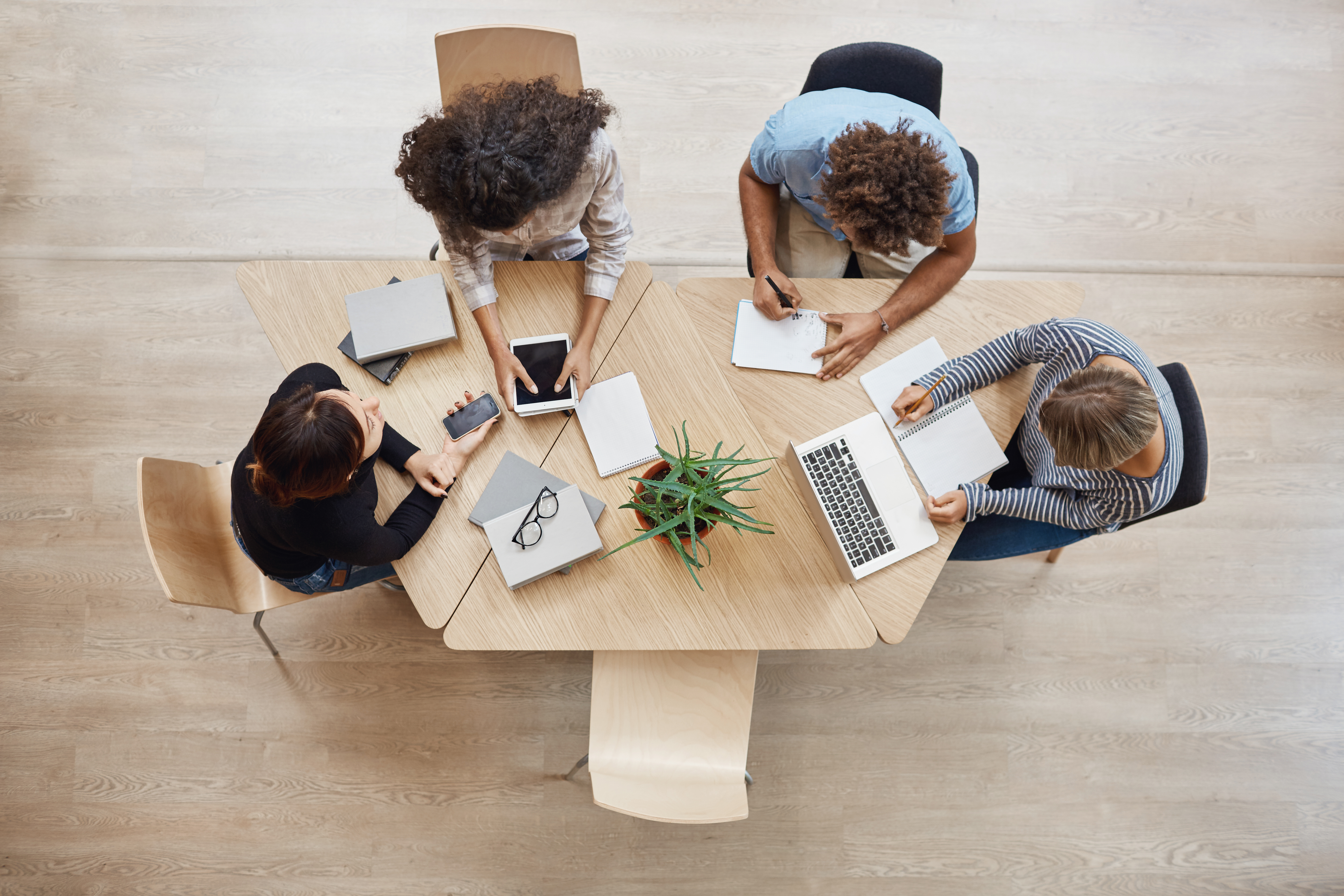 Visão panorâmica de 4 pessoas compartilhando o espaço de trabalho num escritório coworking.